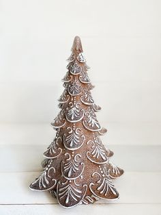 a small ceramic christmas tree sitting on top of a white table next to a wall