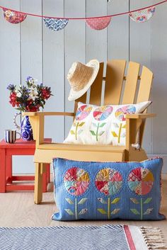 a wooden chair sitting in front of a blue wall with flowers and hats on it