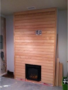 a room with a fire place in the middle and wood paneling on the wall