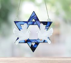 two white doves on a star of david ornament hanging from a chain