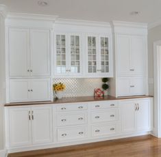 a kitchen with white cabinets and wood flooring in the middle of it's walls