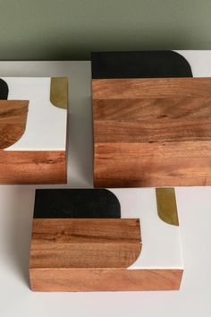 three pieces of wood sitting on top of a white table next to black and gold trim