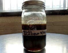 a glass jar filled with liquid sitting on top of a table next to a window