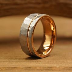 a gold wedding band with two different designs on it, sitting on top of a wooden surface