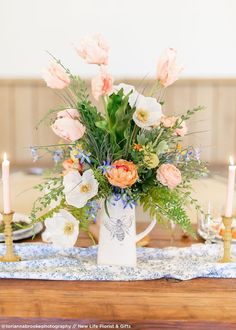 a vase filled with lots of flowers sitting on top of a table next to candles