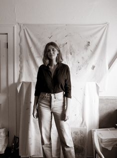 a black and white photo of a woman standing in front of a painting