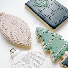 three decorated cookies sitting next to each other on a white counter top with christmas decorations