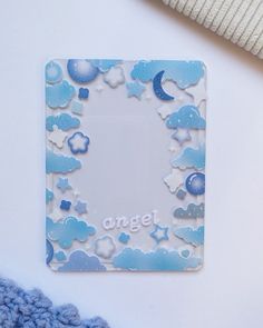 a blue and white photo frame sitting on top of a table next to a knitted blanket