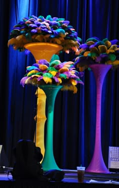 three tall colorful vases sitting on top of a table in front of a blue curtain