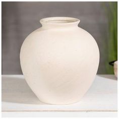 a white vase sitting on top of a table