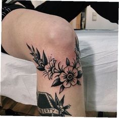 a woman's leg with black and white flowers on it, next to a bed