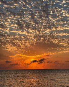 the sun is setting over the ocean with clouds in the sky and on the water