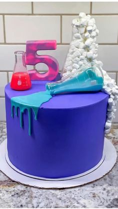 a purple cake with blue icing and some red liquid on the top that says 5