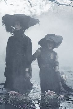 two women dressed in black are standing in the water