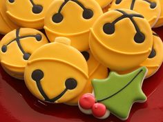 decorated cookies with smiley faces and holly decorations on a red platter, ready to be eaten