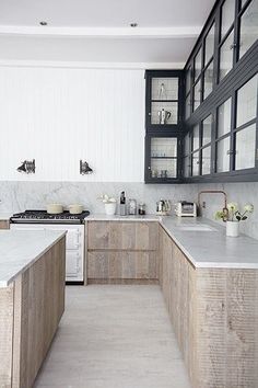 a kitchen with marble counter tops and wooden cabinets, along with black glass doors on the windows