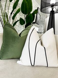 two green and white pillows sitting on top of a couch next to a black lamp