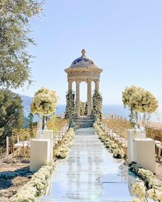 an outdoor ceremony setup with white flowers and greenery on the ground, surrounded by trees