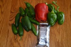 some green and red peppers sitting on top of a wooden table next to a bag of chips