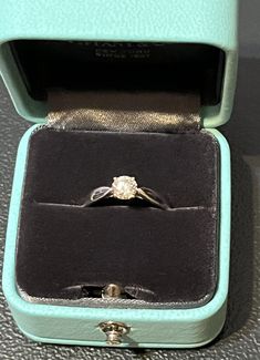 an open ring box with a diamond in it