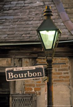 a lamp post with a street sign on it next to a brick wall and roof