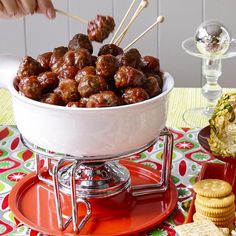 a bowl filled with meatballs next to crackers and crackers on a table