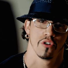 a man wearing glasses and a hat making a funny face with his tongue sticking out