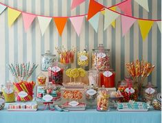 an assortment of candy and candies displayed on a table in front of striped wallpaper