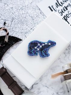 a blue beaded brooch sitting on top of a white box next to other items