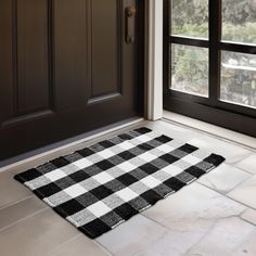 a black and white checkered rug on the floor in front of a door