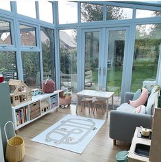 a living room filled with furniture and windows next to a wooden floor covered in toys