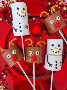 some marshmallows are decorated like snowmen and reindeer faces on a red plate