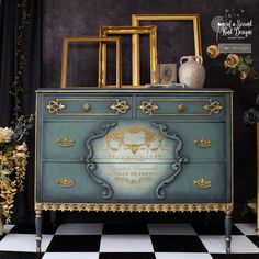 an ornate blue dresser with gold trimmings on the top and bottom, in front of a checkered floor