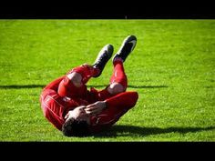 a soccer player laying on the ground with his feet up in the air while wearing red