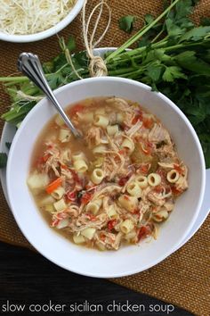 a bowl of chicken noodle soup with noodles and parsley on the table next to it