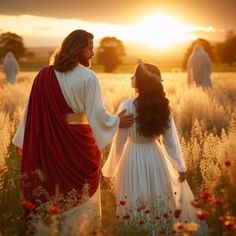 two people dressed in white and red are walking through a field with flowers at sunset