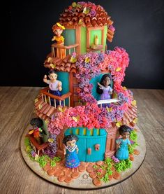 a cake that is shaped like a house with people in the windows and flowers all over it