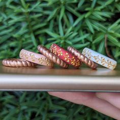 four different colored rings sitting on top of a metal object in front of some plants