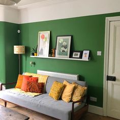 a living room with green walls and yellow pillows on the couch in front of it