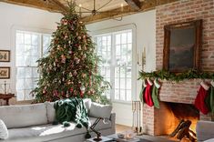 a living room with a christmas tree in the corner and stockings hanging from the ceiling