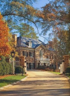 a large brick house surrounded by trees in the fall