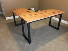 a wooden table with black metal legs in a room next to a brown wall and carpeted floor