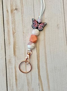 Keep your name tag or ID close to you with this pink butterfly silicone bead lanyard. Made with a breakaway clasp and silver colored metal swivel clip.  Lanyard length is approximately 20 inches from the breakaway clasp to the top of the swivel clip (where the beads attach). Length can be adjusted to be shorter by tying another knot inside the breakaway clasp.  Want a custom color or pattern? Please message me or email me at sincerelyjenn031@gmail.com *Contains small parts that can be a hazard f Pink Lanyards With Keychain For Everyday Use, Pink Lanyard With Keychain For Everyday Use, Pink Beaded Lanyards For Gifts, Pink Lanyard With Key Leash For Gift, Pink Lanyard With Keychain For Gift, Handmade Pink Lanyards For Personal Use, Adjustable Personalized Pink Lanyard, Handmade Pink Lanyards For Everyday Use, Pink Lanyard With Keychain For Personal Use