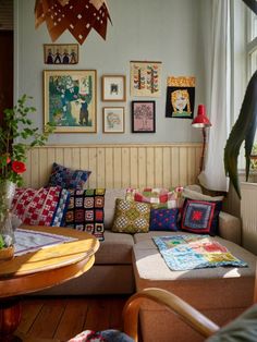 a living room filled with lots of furniture and pictures on the wall above it's windows