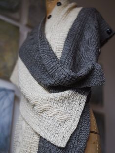 a gray and white knitted shawl sitting on top of a mannequin