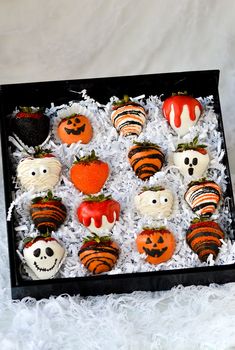 a black box filled with halloween treats on top of white fluffy material covered in frosting