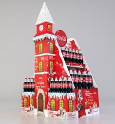 a coca - cola building is made out of cardboard and has snow on the roof