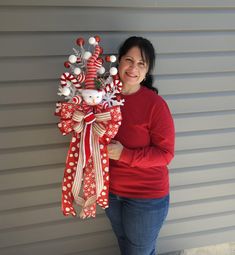 a woman standing next to a wall with a christmas decoration hanging from it's side