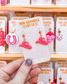 a person holding up some earrings in front of a shelf with other items on it