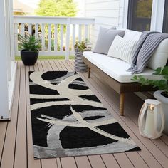 a black and white rug sitting on top of a wooden floor next to a couch